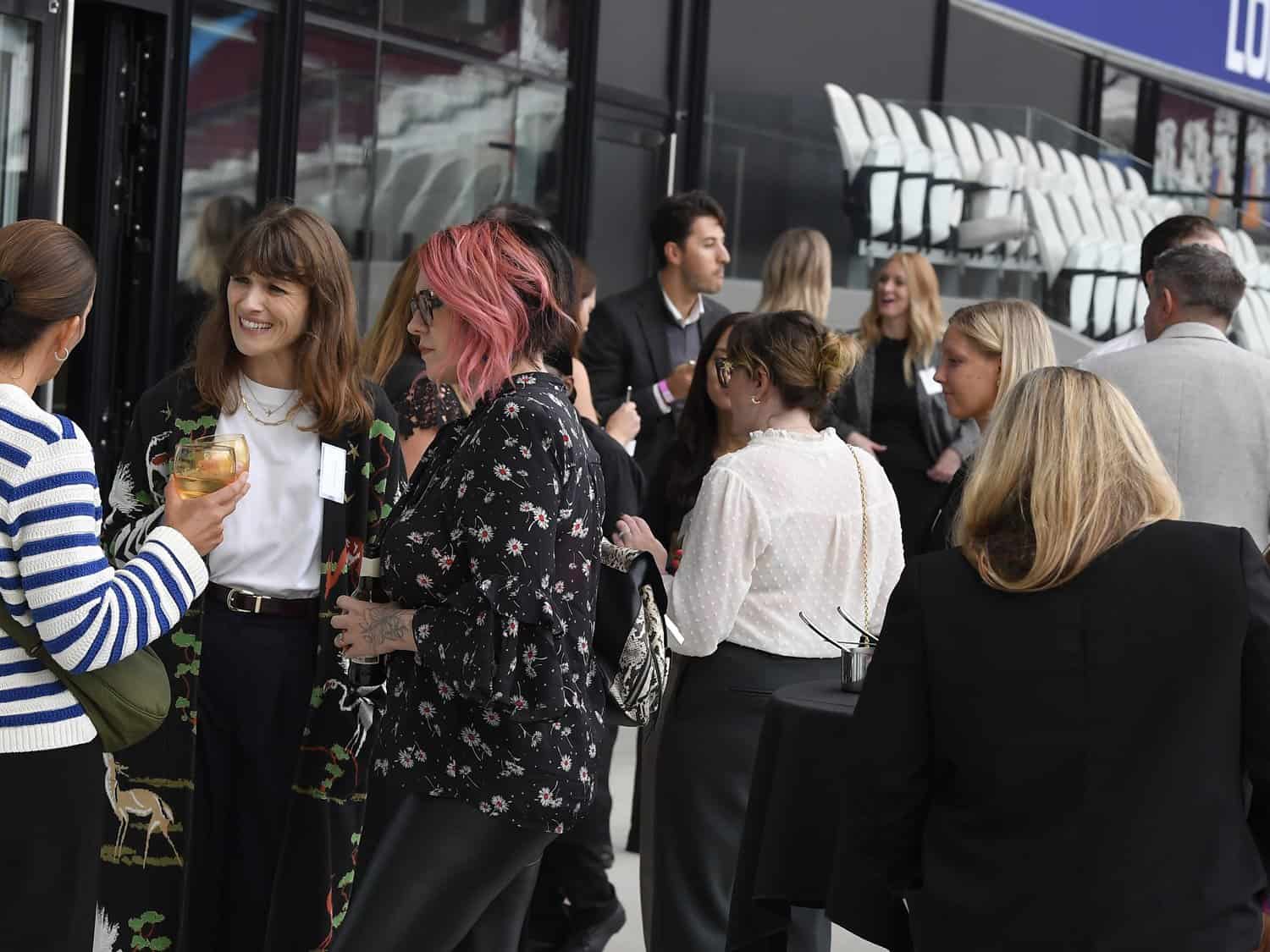 A lively group of people socialising outside a bus at a corporate event in London.