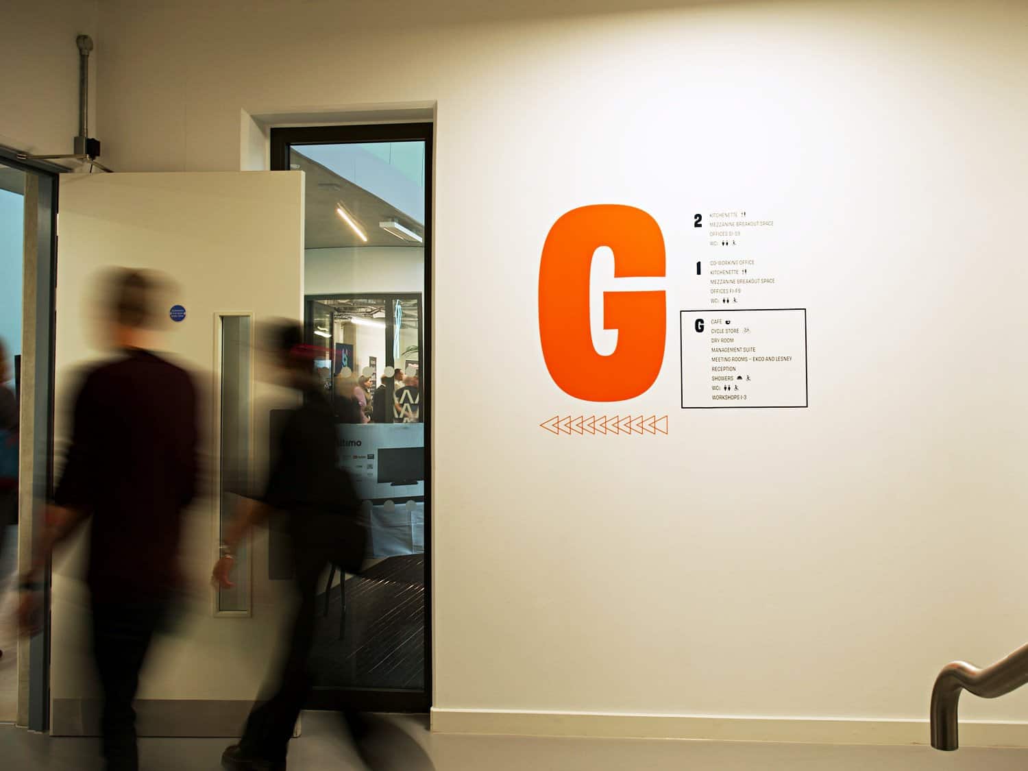 Modern office building interior with blurred people and large G logo.