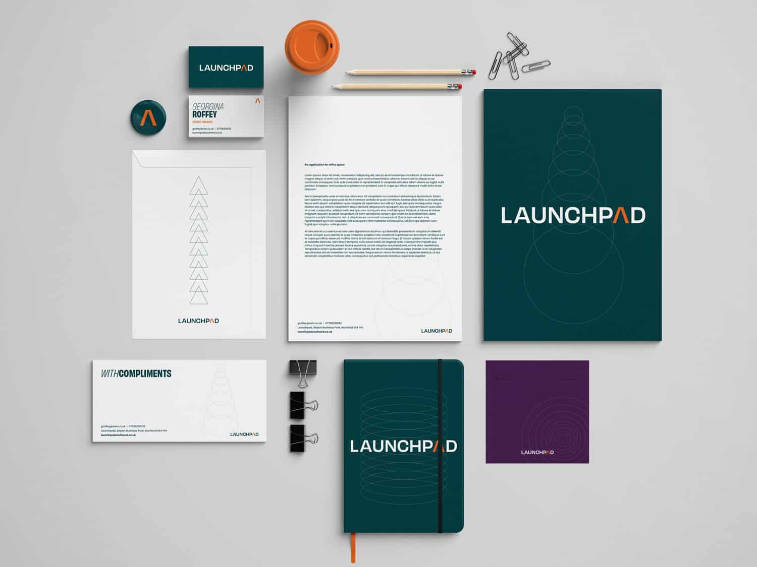 Launchpad branding materials including notebooks, documents, and office supplies arranged on a desk.