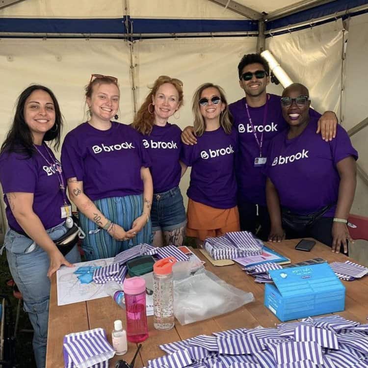 Bright team wearing purple t-shirts at outdoor event, smiling and engaging with visitors.