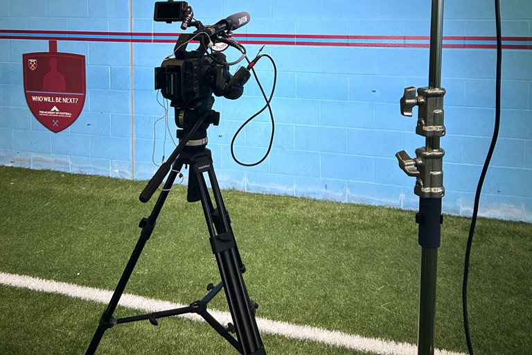 A camera setup on a tripod for sports or event filming outdoors.