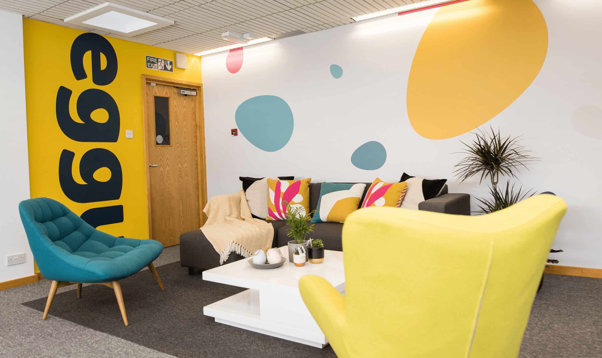 Bright modern office lounge with colourful furniture and wall art, sixredsquares branding.