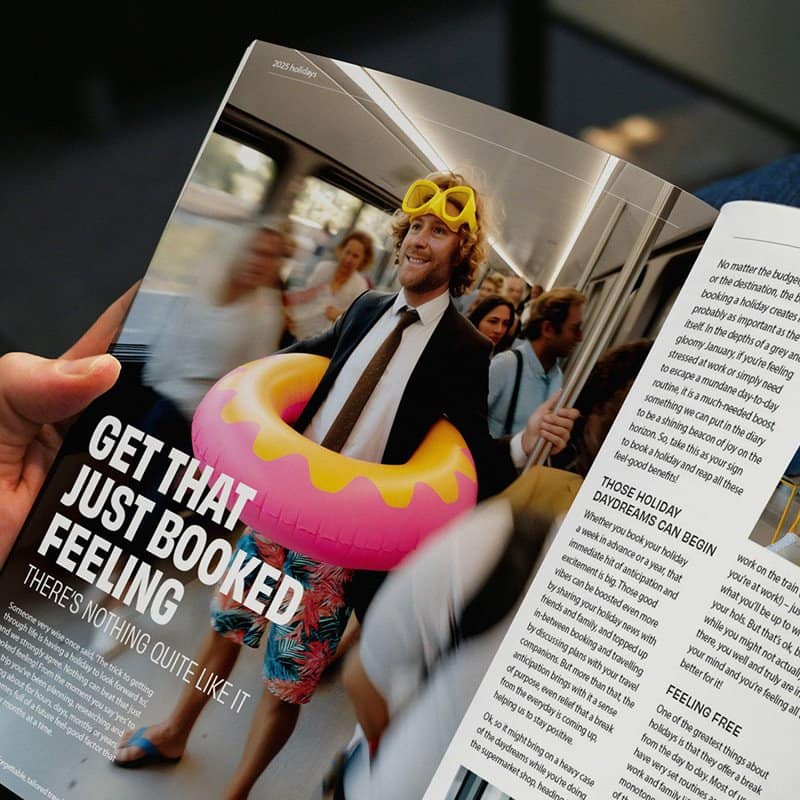 Relaxed man with a beard wearing a suit and yellow goggles, holding a pink inflatable donut, on a bu.