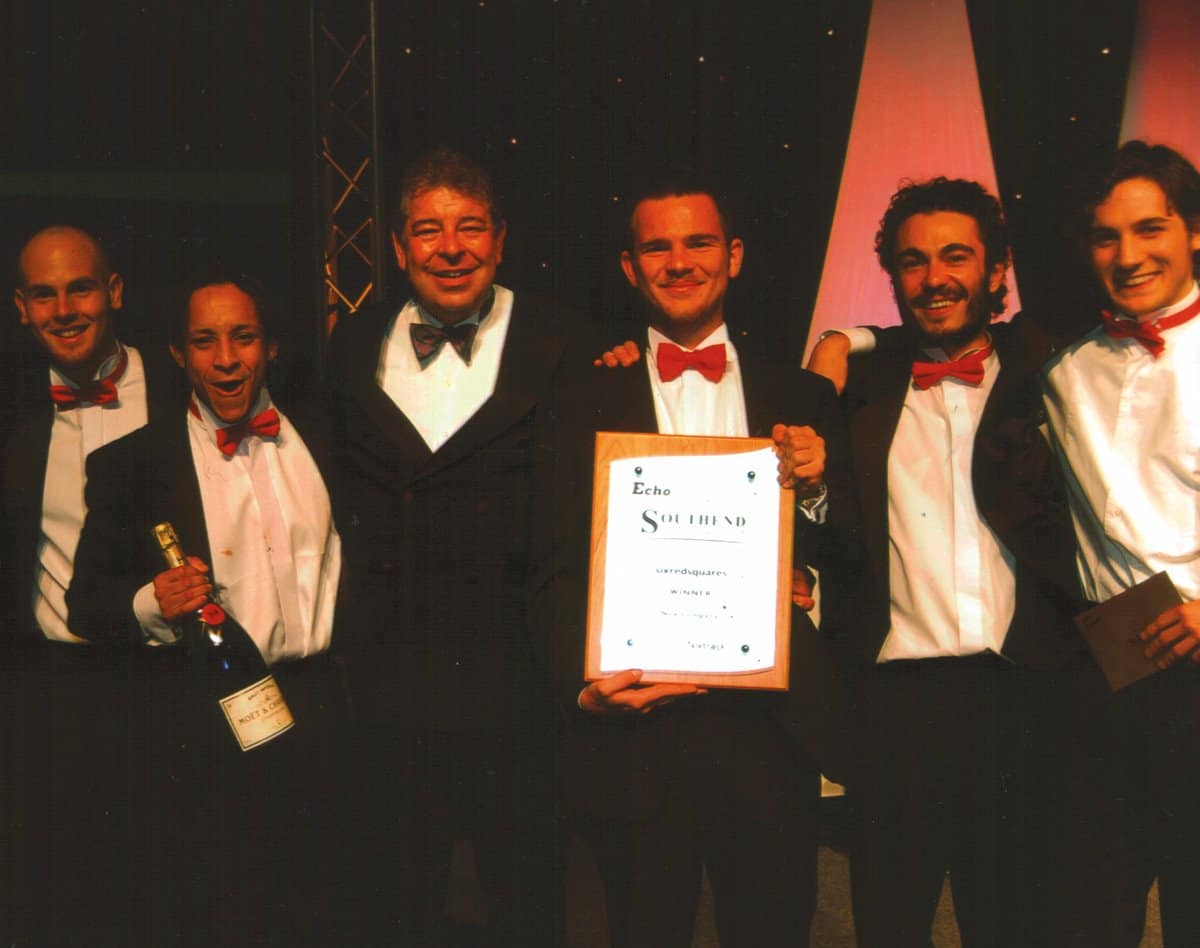 Team receiving award at a formal event with champagne.