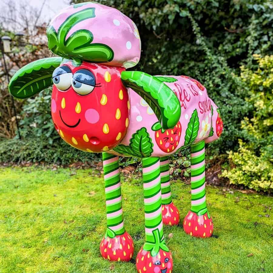 Strawberry-themed inflatable garden sculpture with colourful details and playful design.