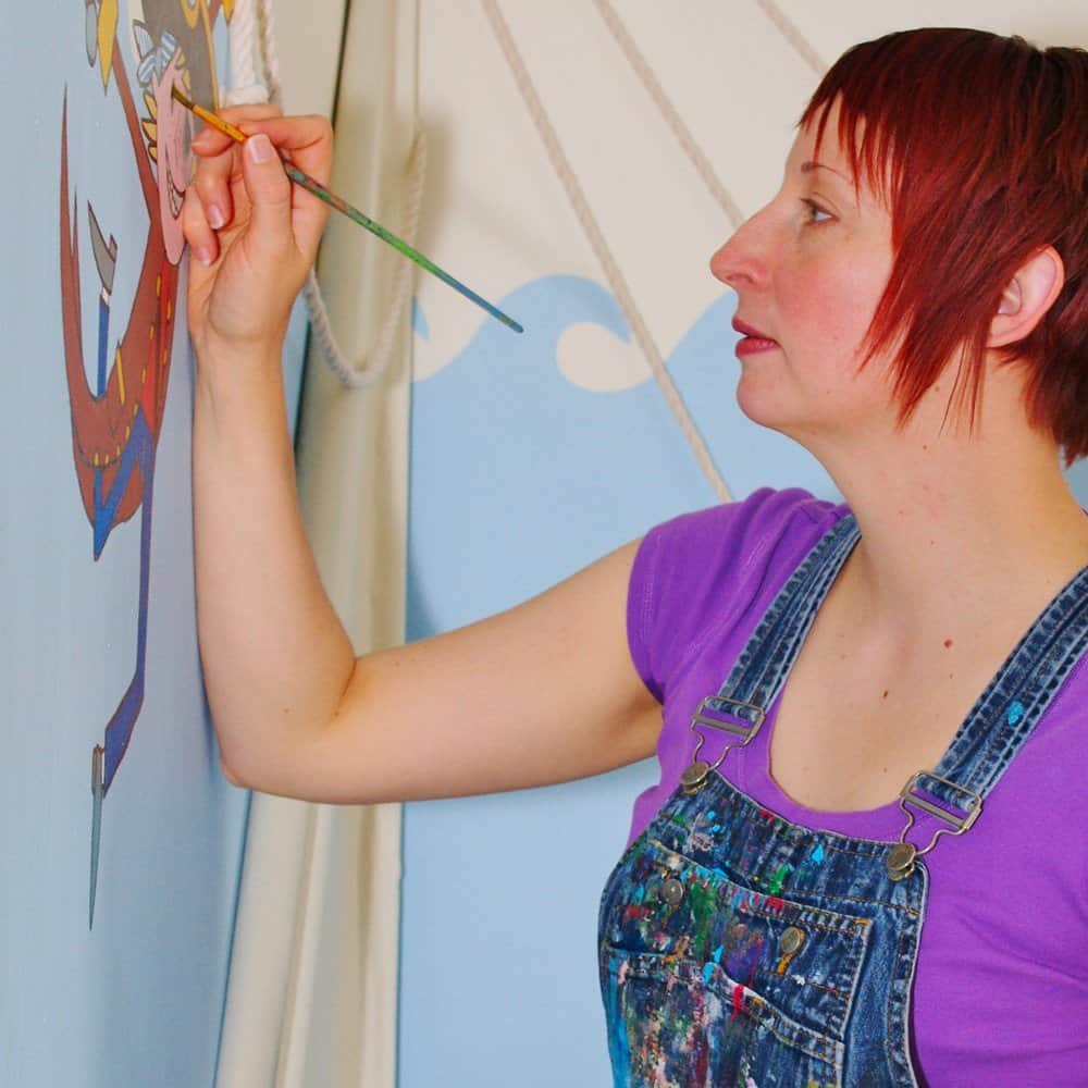 A woman painting a colourful mural on a wall, creative art and interior decoration.
