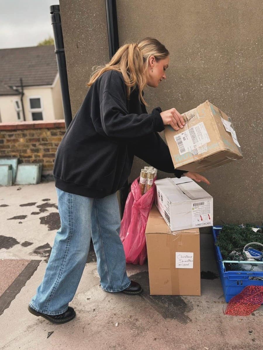 A woman collecting parcels outside a building, delivery and logistics concept.